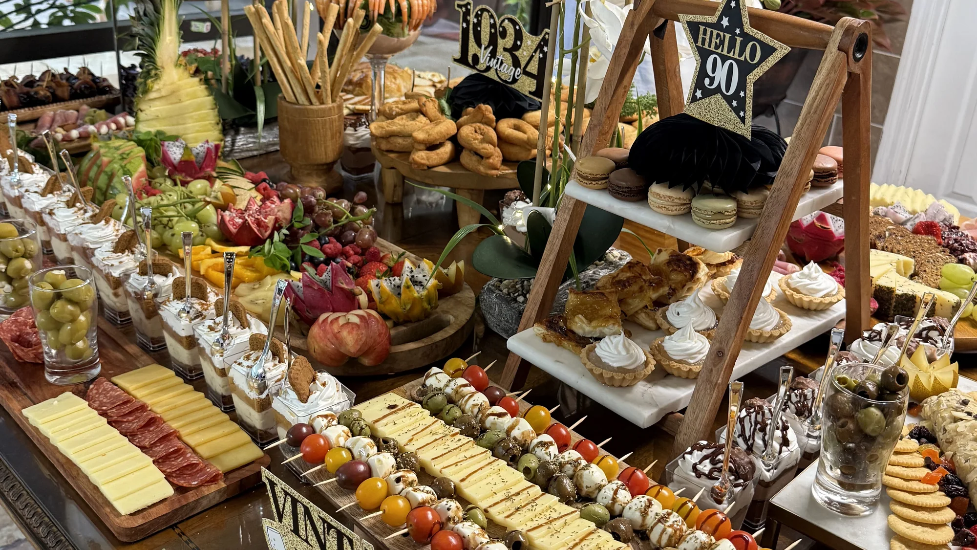 Milestone celebration table with charcuterie, fruit, desserts and composed bites